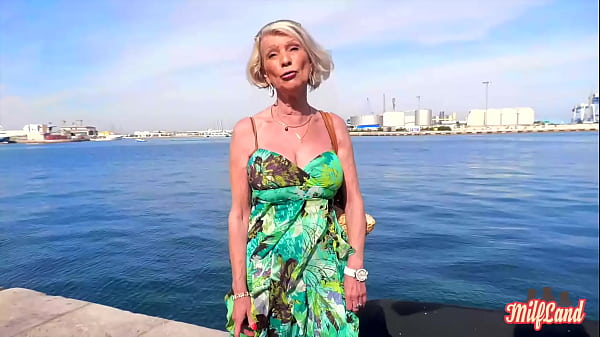 Мамочка блондиночка стоит на берегу моря и снимается